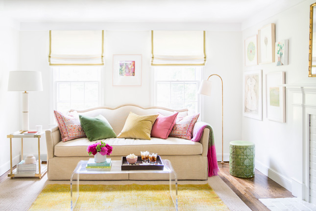 The beautiful design work of McGrath II--light, bright living room with white walls, cream sofa, colorful throw pillows, lucite coffee table and a perfect reading lamp. 