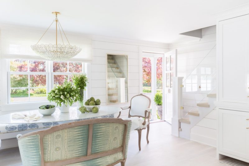 A dreamy cape cod style home designed by Raquel Garcia. White interiors, brass and lucite details, open floor plan, and shiplap.