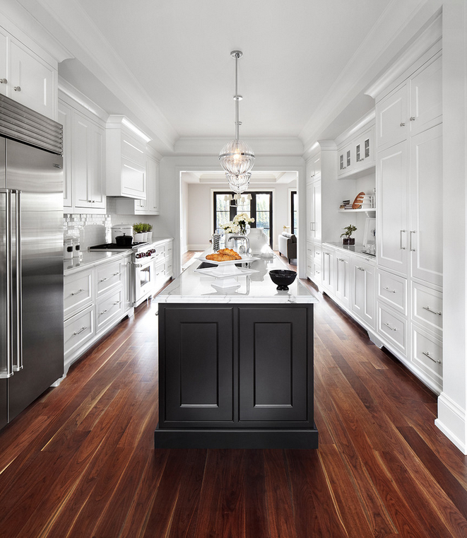 Striking white kitchen with dark wood floors.