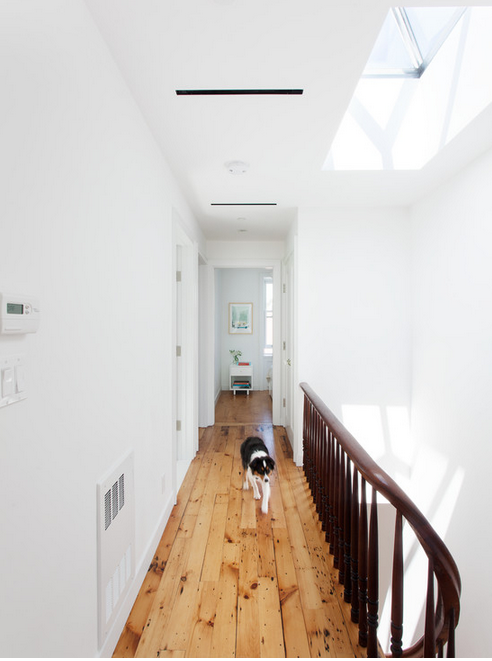 row house hallway with skylight, white walls and beautifully restored wood floors. 