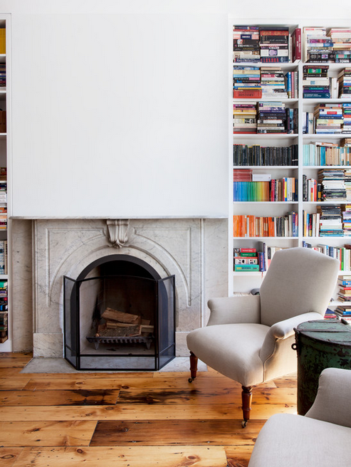 Floor to ceiling bookshelves, a fireplace, and a perfectly situated chair. 