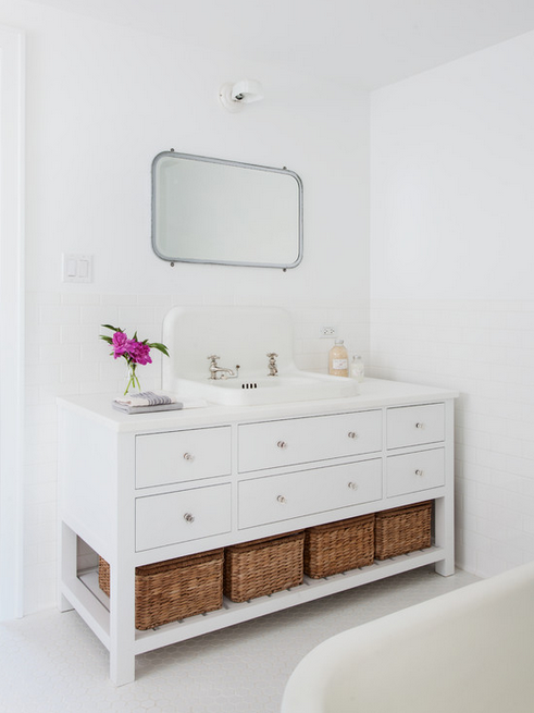 Perfectly serene all-white bathroom with subway tiling, vanity with lots of drawers and baskets for extra storage beneath. 