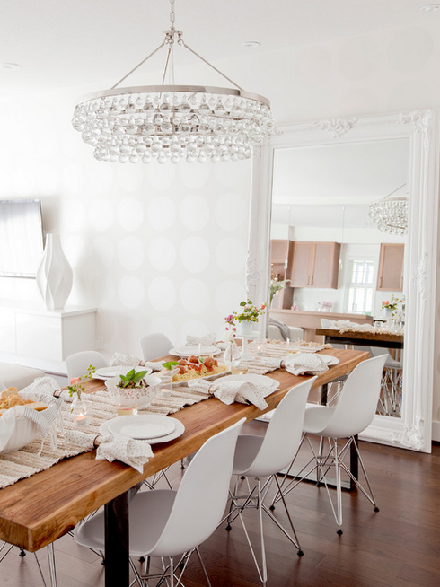 Gorgeous and serene dining space with beautiful beaded light fixture, large leaning mirror, modern white chairs, and subtle polka-dotted walls. 