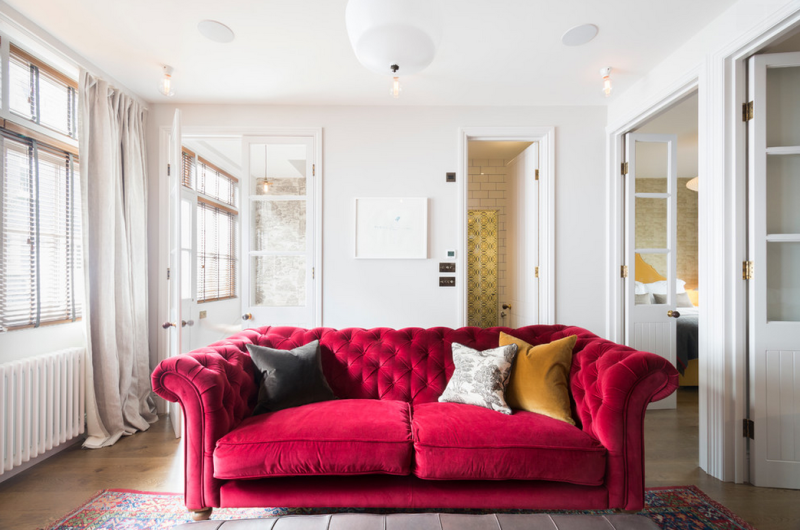 Dreamy sitting room with rich creamy tones and a bright fuchsia-red tufted sofa 