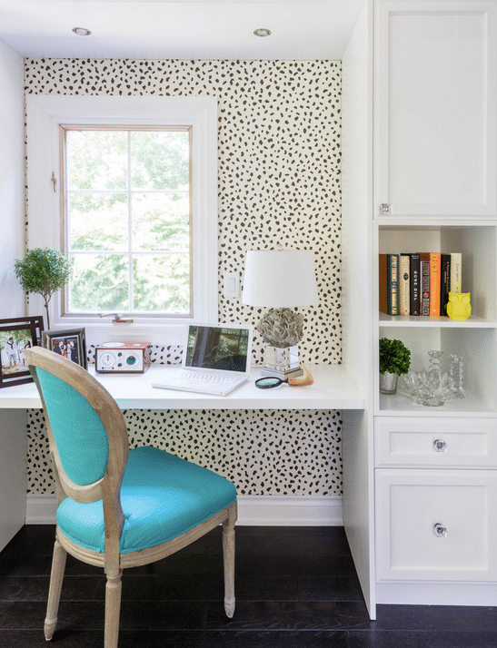 Charming workspace with spotted wallpaper and a bright aqua chair. 