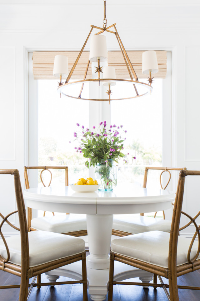 Dining area with bamboo chairs and a stunning brass light fixture by Studio McGee
