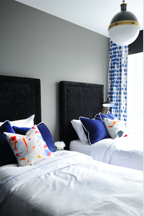 An easy yet sophisticated take on twin beds. The black, velvet headboards are balanced out with whimsically patterned curtains and throw pillows.