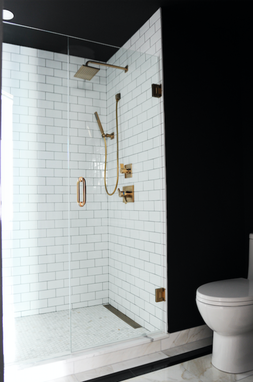 Perfectly dramatic bathroom with black walls, white subway tiles and brass fixtures. 