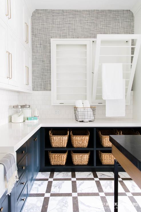 Seriously dreamy laundry room design. Navy cabinets, beautiful tile, stunning fixtures, and wallpaper to boot.  