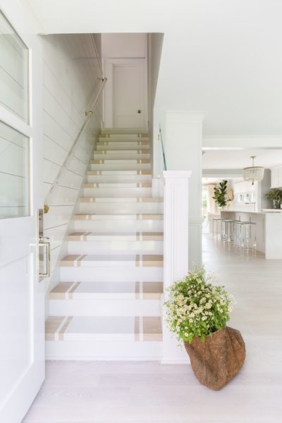 A dreamy cape cod style home designed by Raquel Garcia. White interiors, brass and lucite details, open floor plan, and shiplap. 